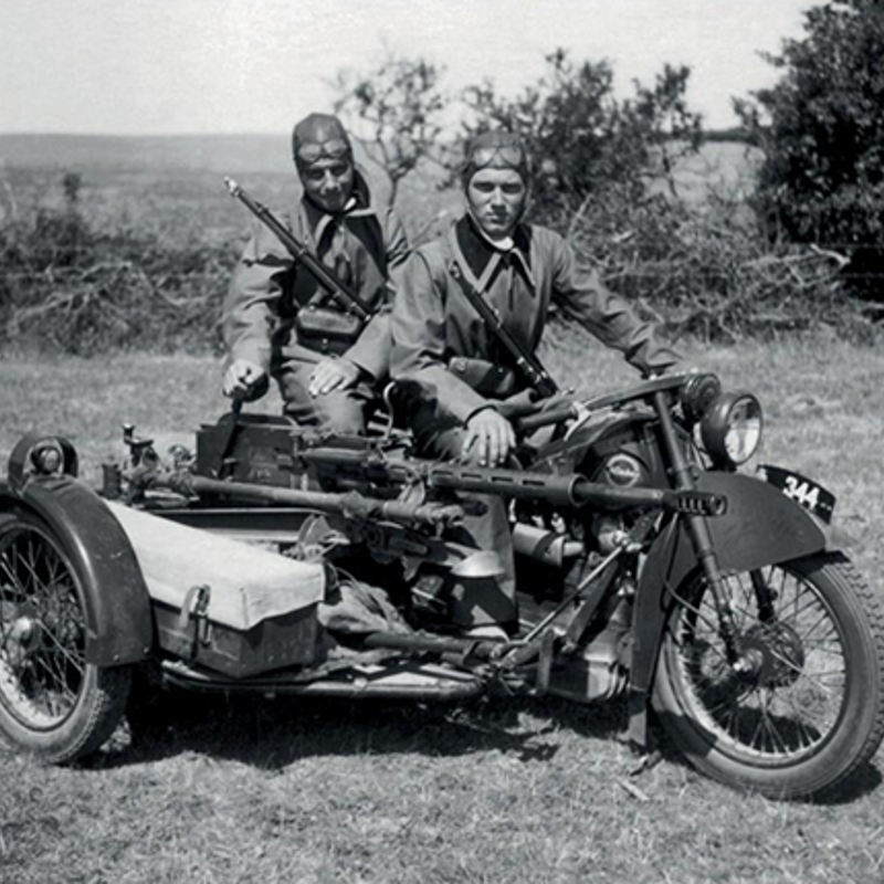 Foto af en motocykel med to soldater placeret på. Motorcyklen er udstyret med et rekylgevær på siden. 